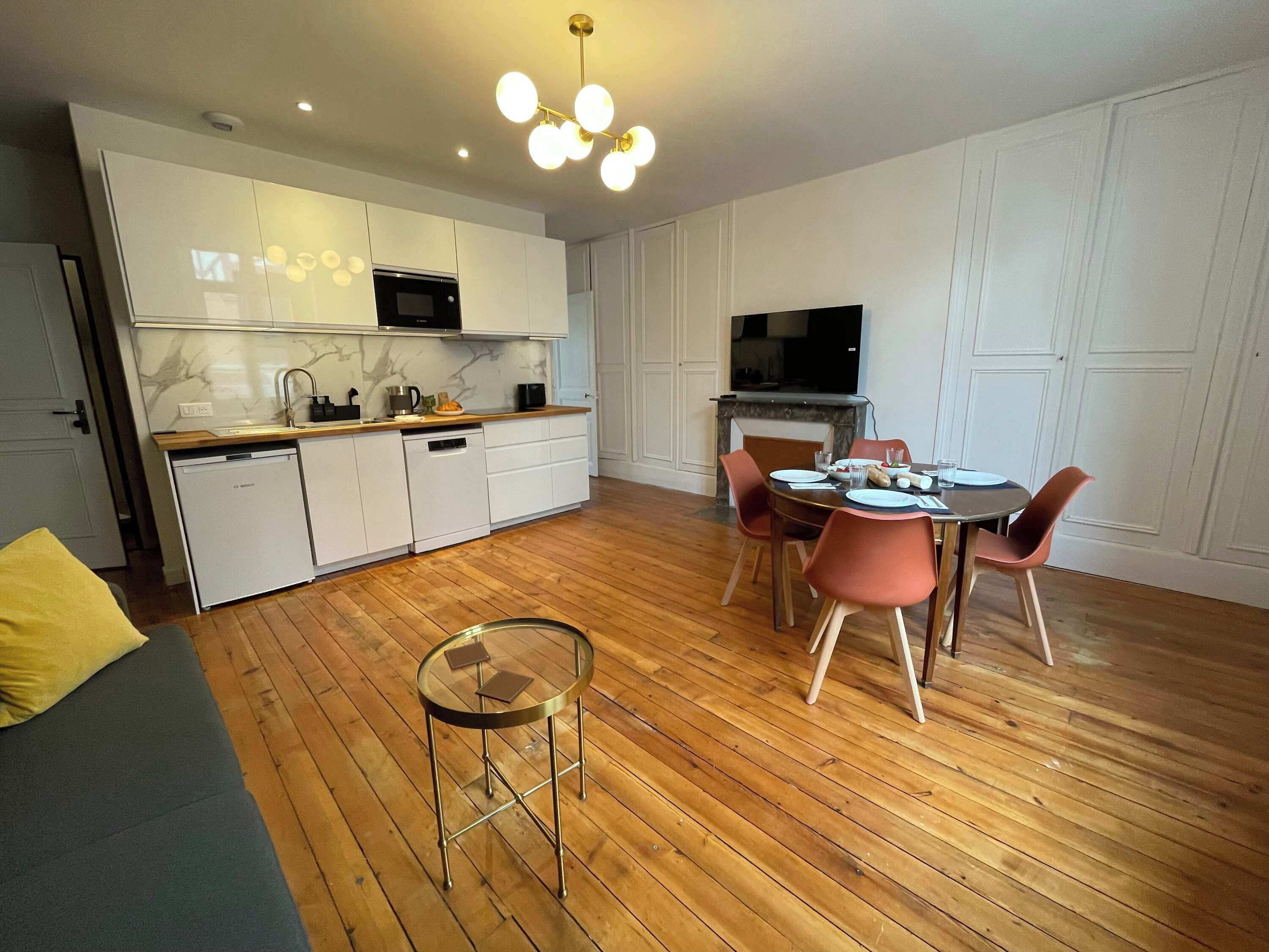 Une cuisine moderne avec des meubles blancs, un four à micro-ondes encastré et un coin repas comprenant une table ronde et des chaises.