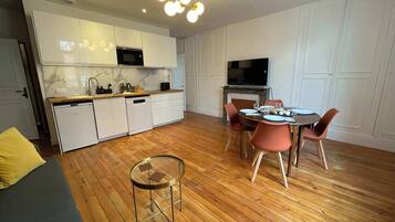 Une cuisine moderne avec des meubles blancs, un four à micro-ondes encastré et un coin repas comprenant une table ronde et des chaises.