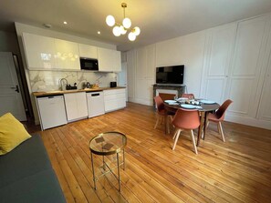 A modern kitchen with white cabinets, a built-in microwave, and a dining area with a round table and chairs. - Queen Bed • Fully Equipped Quiet Apartment • Amiens Centre • 5-min Walk to Station • Parking on Site (Amiens)