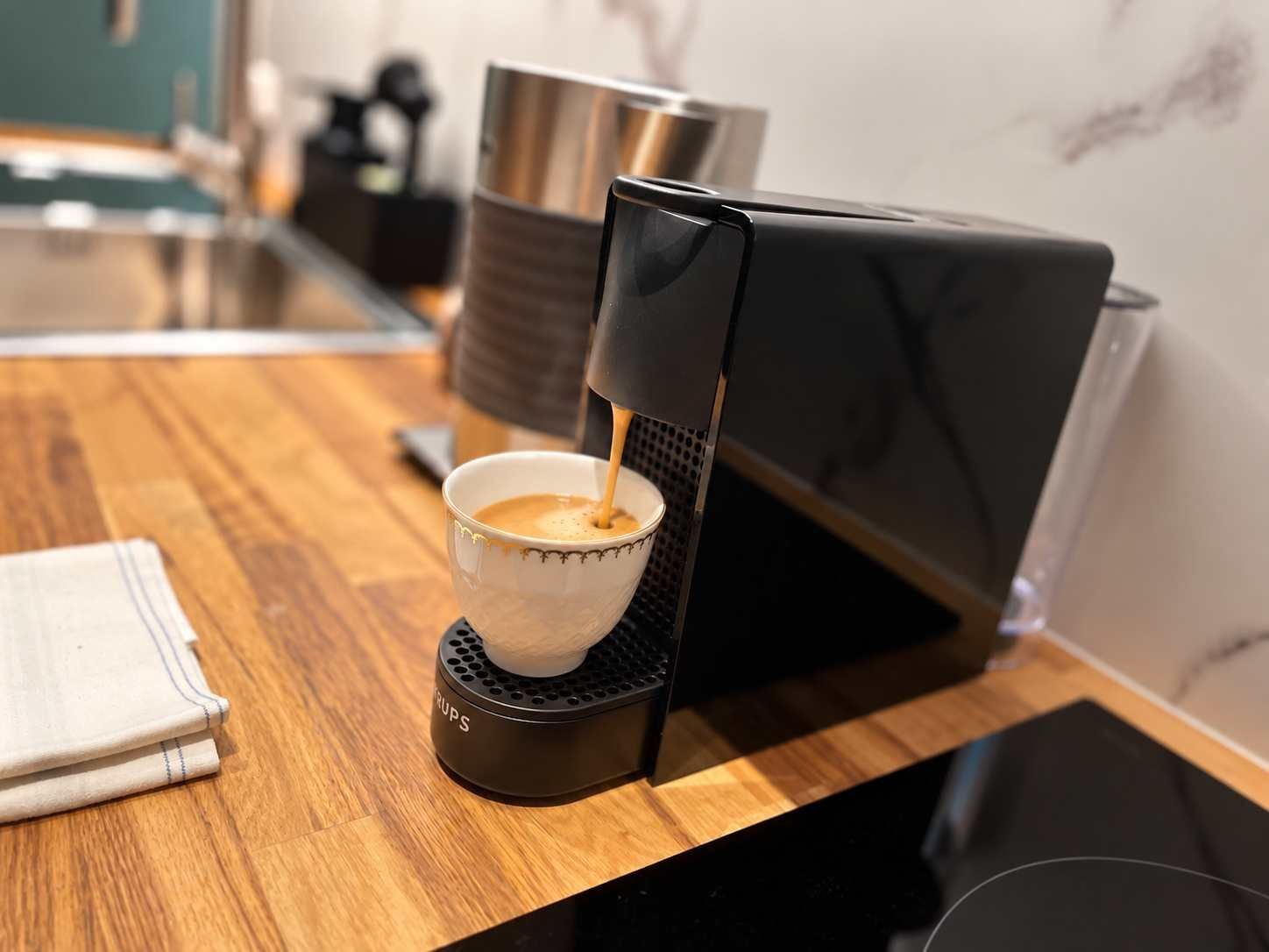 Máquina de café servindo café numa chávena sobre uma bancada de madeira.