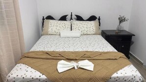 Un letto rifatto con una coperta a pois, una coperta marrone e un cuscino bianco.