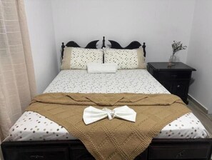A neatly made bed with a polka dot bedspread, a brown throw blanket, and a white pillow. - Suite with Pool and Nature View (Achada Fazenda)
