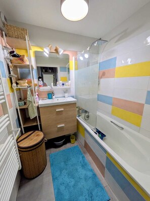 A bathroom with a shower, a sink, a mirror, and a storage shelf. - Lyon Center Apartment with private garden & garage (Lyon)