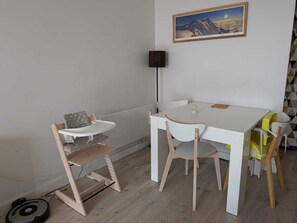 A small dining area with a white table and chairs, a baby high chair, and a painting on the wall. - Lyon Center Apartment with private garden & garage (Lyon)