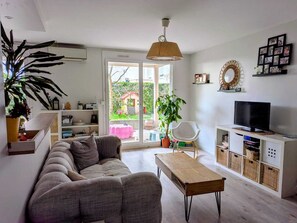 A modern living room with a sofa, a wooden coffee table, a TV, and a large window. - Lyon Center Apartment with private garden & garage (Lyon)