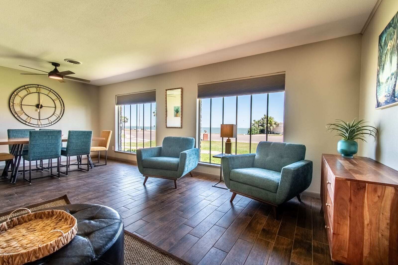 Uma sala de estar ampla com área de jantar, grandes janelas e vista, e um ventilador de teto.