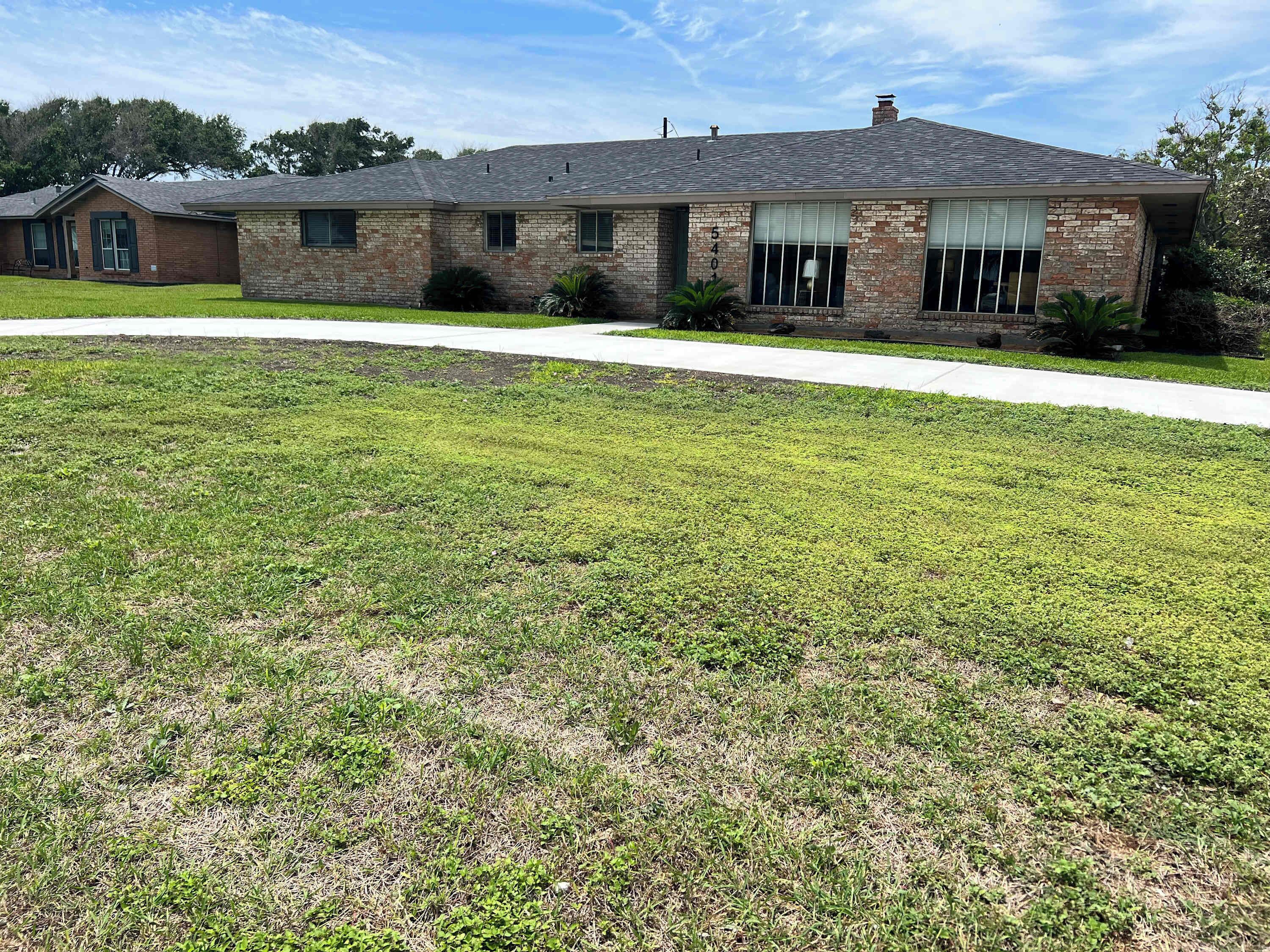 A two-story house with a brick facade, a front yard, and a driveway.