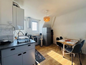 Eine kompakte Küche mit modernen Geräten, ein Essbereich mit Tisch und Stühlen und ein Fenster, das für natürliches Licht sorgt.