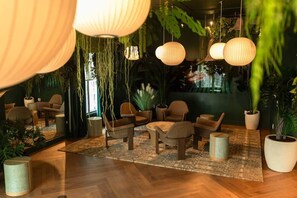 Un espace salon accueillant, avec des meubles en osier, des lanternes en papier suspendues et des plantes en pot.