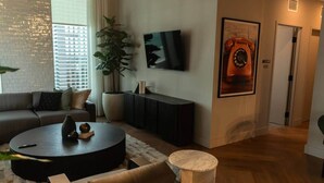 Ein modernes Wohnzimmer mit einer Couch, einem runden Couchtisch, einem Fernseher, einer Topfpflanze und einem Marmor-Element.