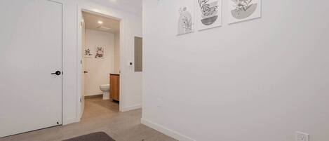 Un couloir avec une porte, un tapis et trois œuvres d’art accrochées au mur.