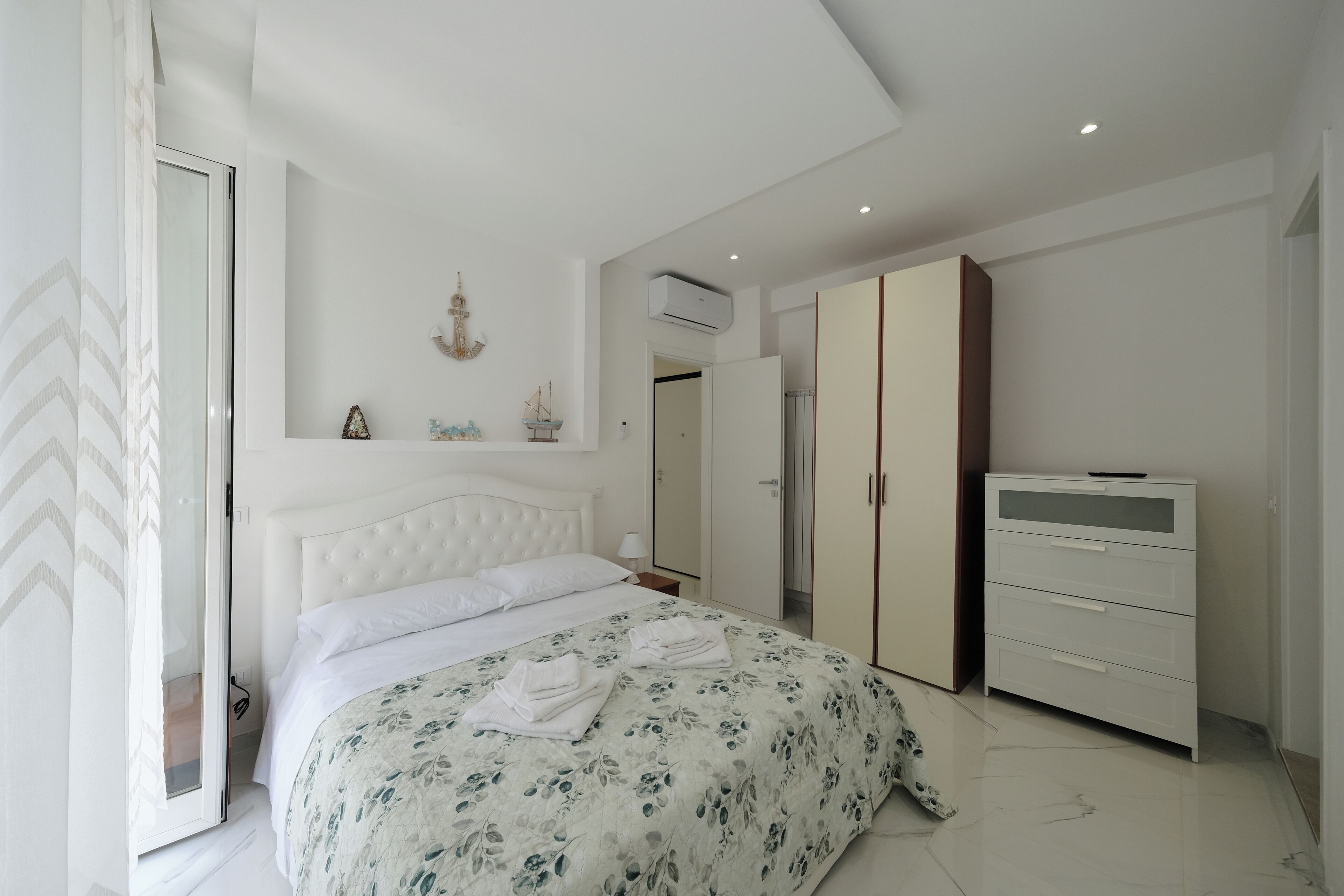 Une chambre à coucher comprenant un lit, une armoire, une commode et un miroir.
