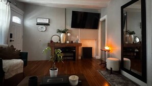 A living room with a sofa, coffee table, TV, fireplace, and a large mirror. - Villages romantic house at Ridgfield near nyc (Ridgefield Park)