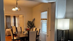 A dining area with a wooden table and chairs, a potted plant, and a piano. - Villages romantic house at Ridgfield near nyc (Ridgefield Park)