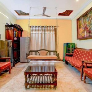 A living room with a sofa, a coffee table, a swing chair, and a ceiling fan.