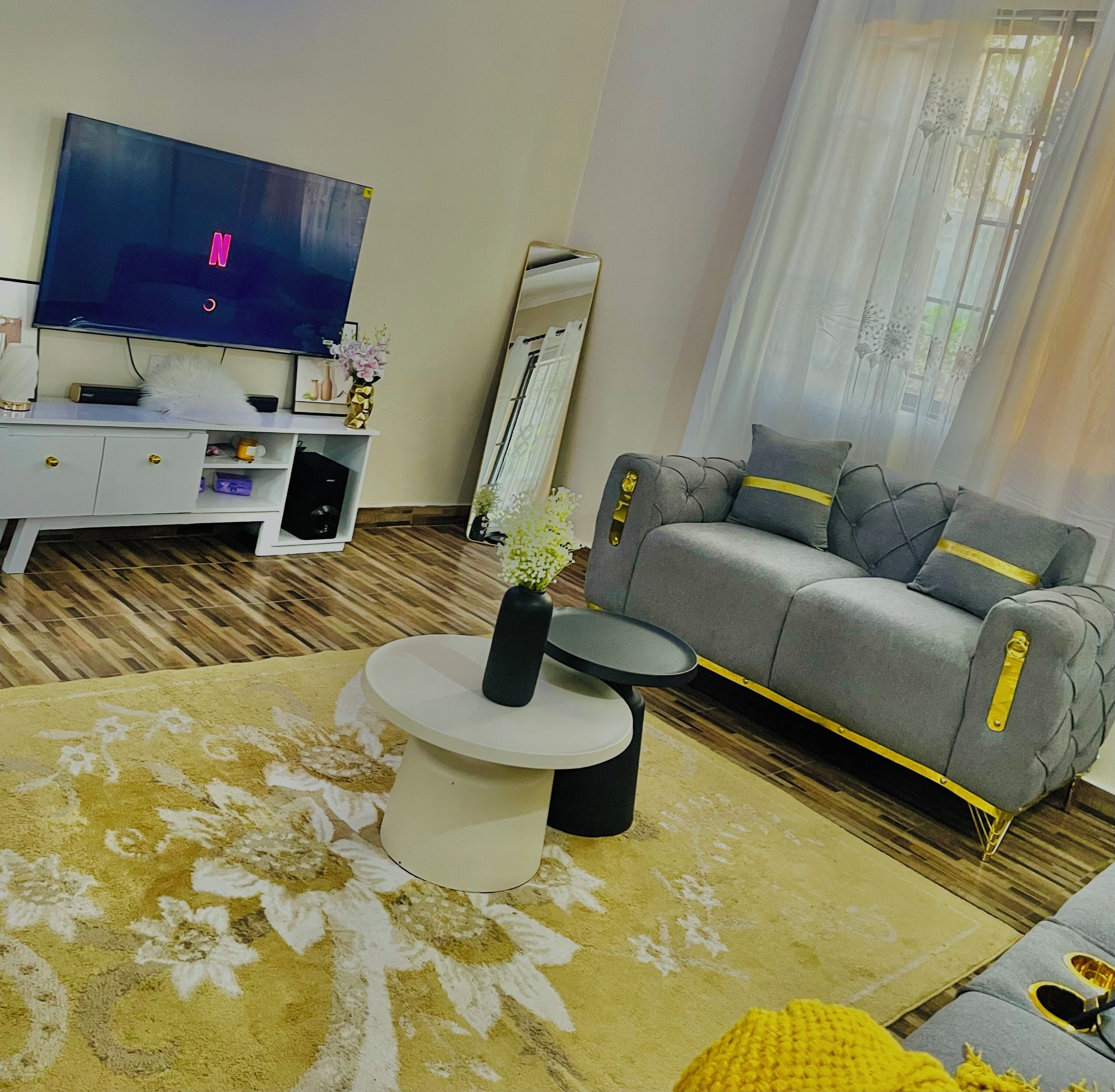 A modern living room with a flat-screen TV, a sofa, a coffee table, and a patterned rug.