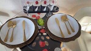 A dining table set with gold cutlery, white plates, and a black tray with red rose petals. - We offer peace & serenity…wellcome to our home away from hom (Dar es Salaam)