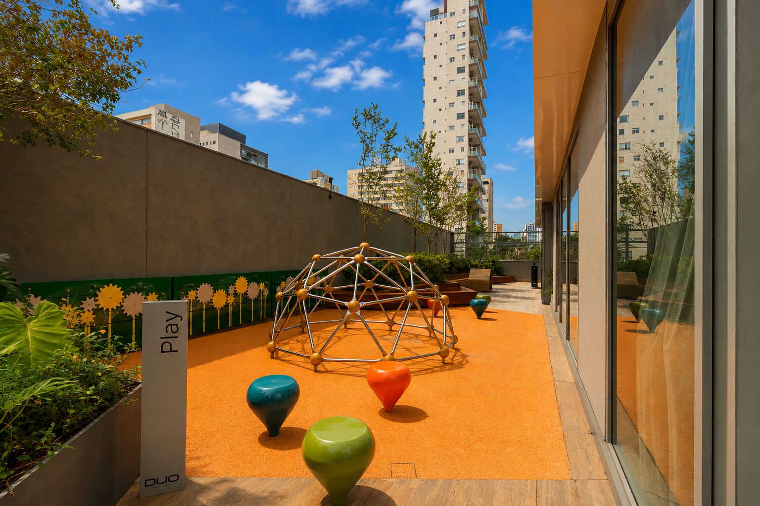 A rooftop play area with a geodesic dome, colorful spherical sculptures, and a 'Play' sign.