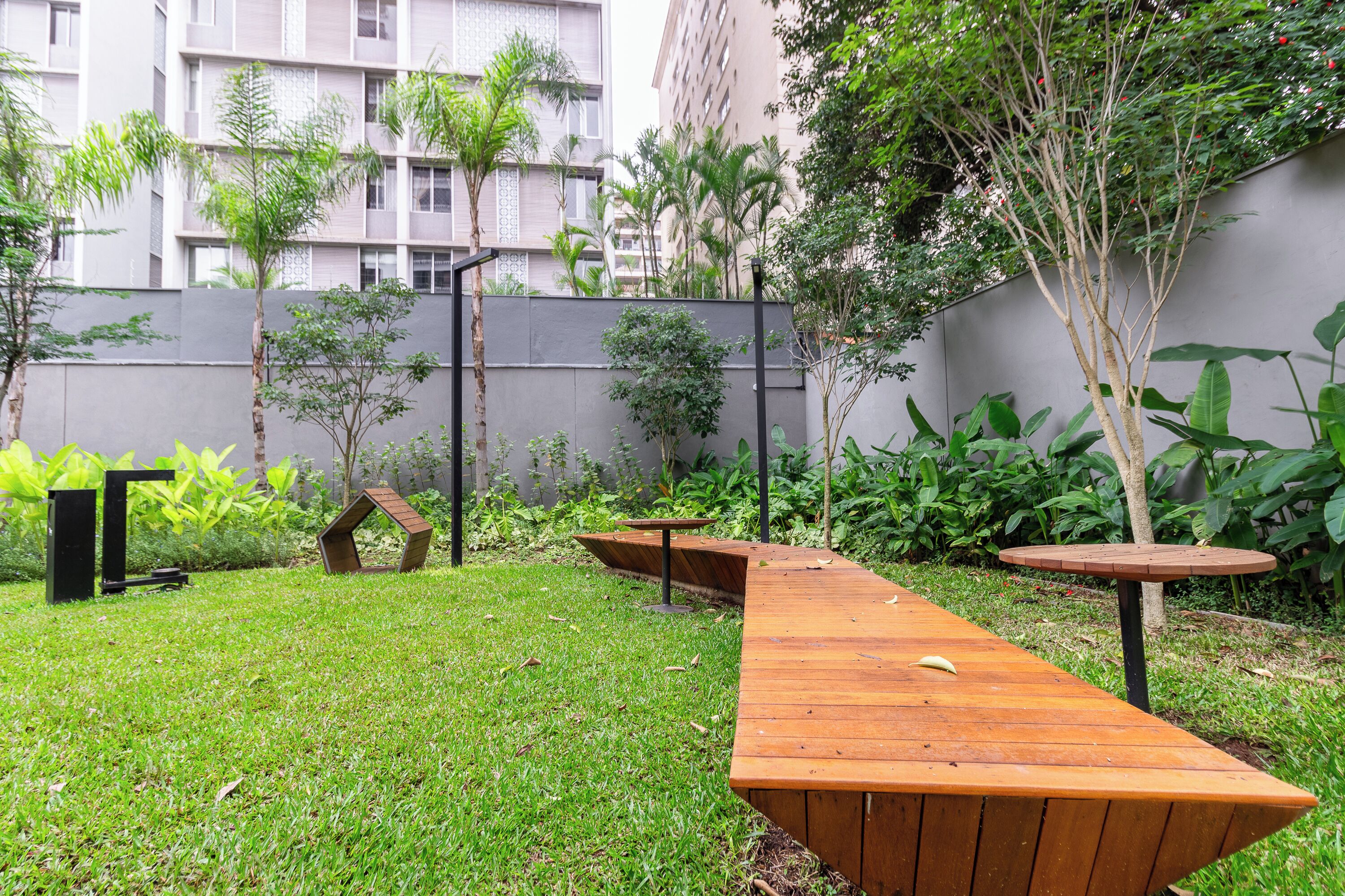 Un patio con un banco de madera, una mesa pequeña y un árbol decorativo.