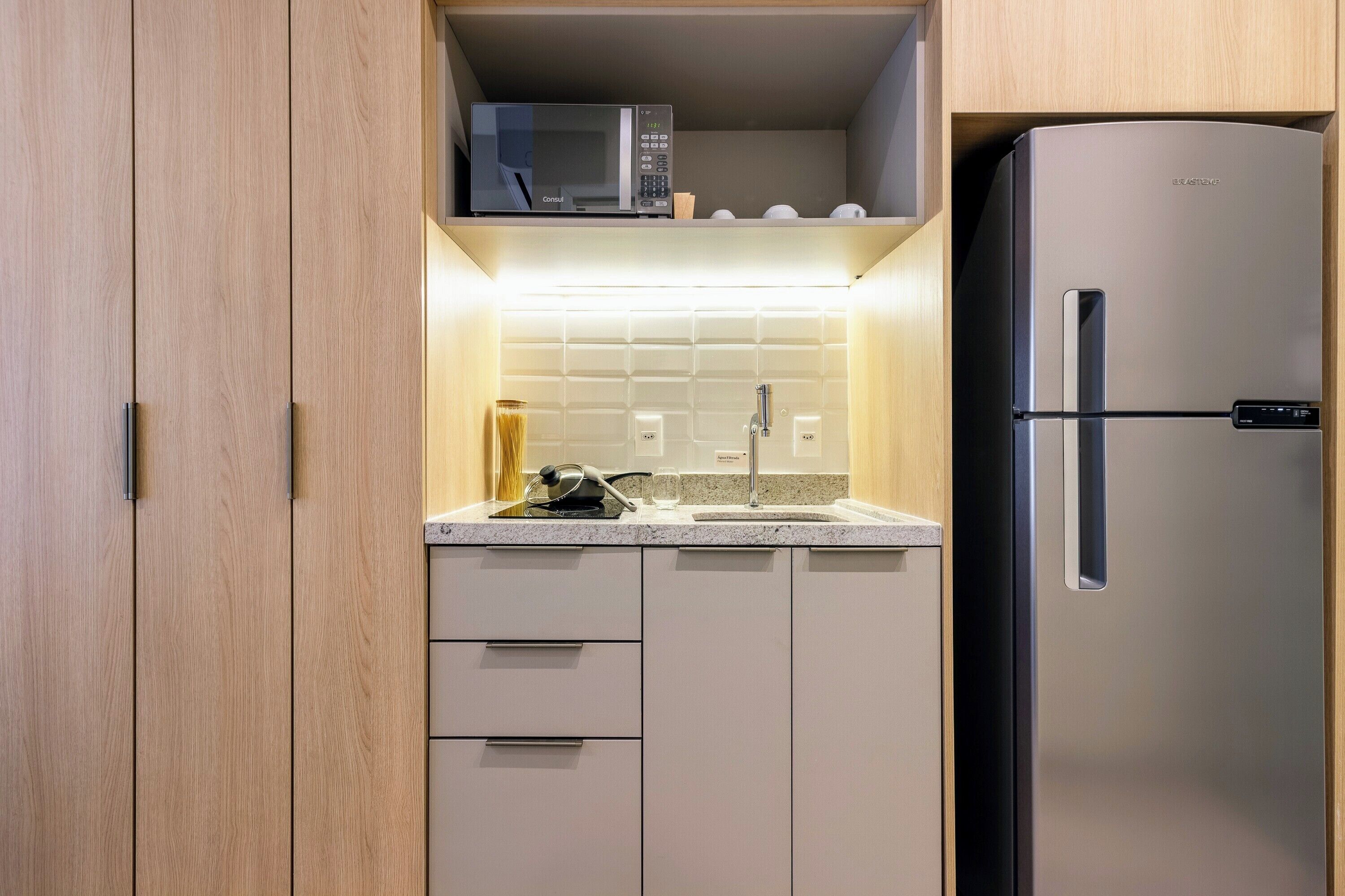 A kitchen with a microwave, sink, and stainless steel refrigerator.