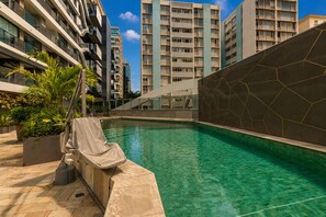 Una piscina al aire libre, sillones reclinables de piscina