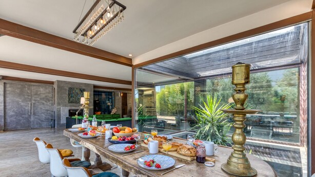 A modern dining area with a long table, chairs, and a large window. - Spacious Loft Near the Center with Garden and Pool (Pézenas)