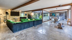 A spacious living area with a sectional sofa, a piano, and a glass wall leading to a balcony. - Spacious Loft Near the Center with Garden and Pool (Pézenas)