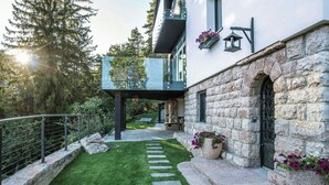 Una casa moderna con fachada de piedra, un balcón y un césped cuidado.