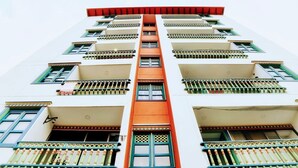 A multi-story building with balconies, a central orange stripe, and a red roof. - Apto Plaza Principal /Vista Embalse/frente Autobús (Guatapé)