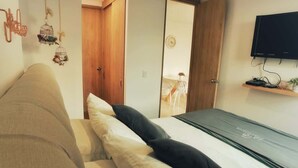 A bedroom with a bed, a sofa, a TV, and a wooden wardrobe. - Apto Plaza Principal /Vista Embalse/frente Autobús (Guatapé)