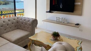 A living room with a sofa, a coffee table, and a TV mounted on a wooden wall. - Apto Plaza Principal /Vista Embalse/frente Autobús (Guatapé)