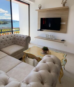 Ein Wohnzimmer mit einer Couch, einem Couchtisch und einem an einer Holzwand montierten Fernseher.