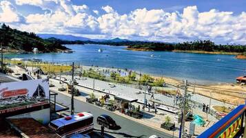 A waterfront hotel with a view of the sea, a pedestrian walkway, and a parking area.