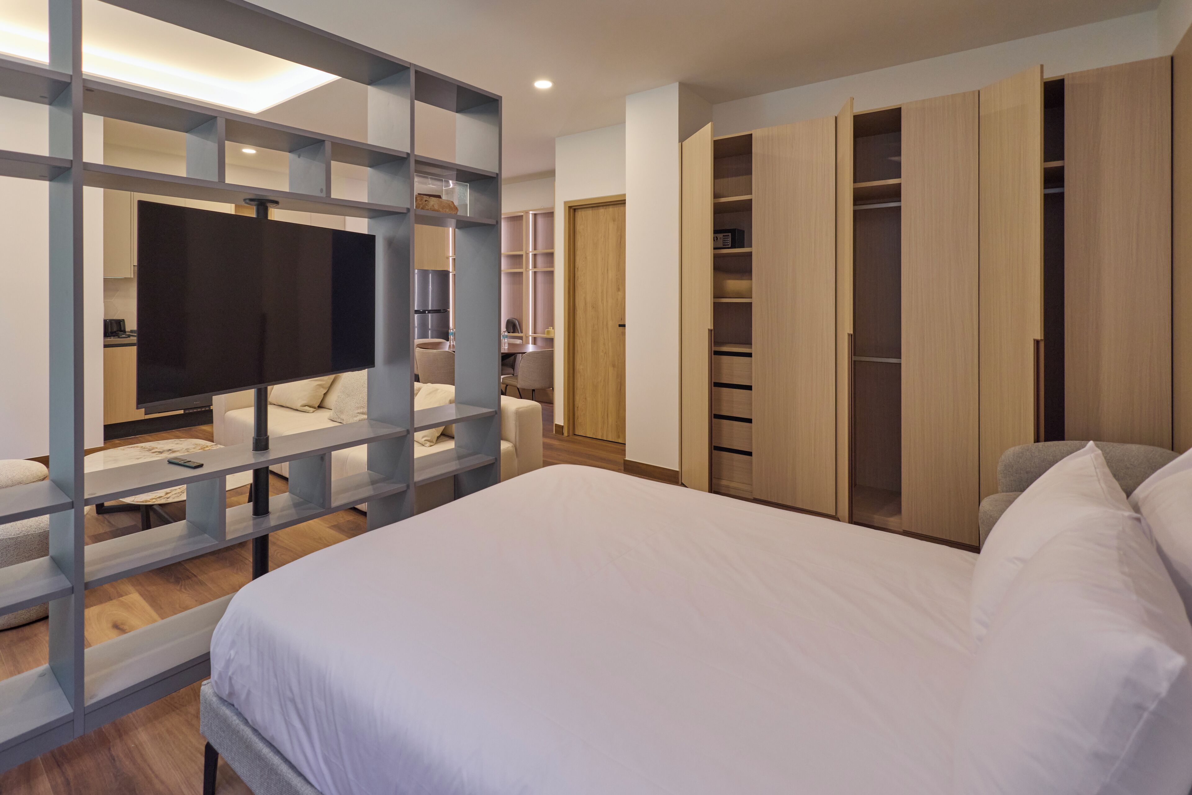Een moderne slaapkamer met een groot bed, een televisie, een bureau en inbouw kasten.