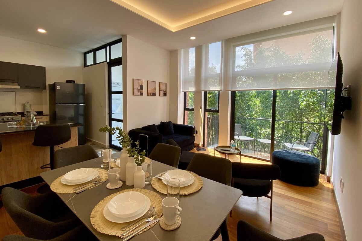 Una cocina moderna con comedor, ventanas amplias y un balcón con mobiliario exterior.