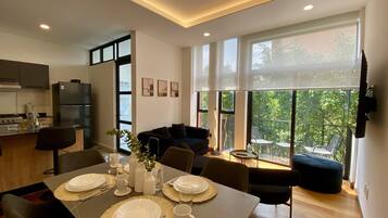 A modern kitchen with a dining area, large windows, and a balcony with outdoor furniture.