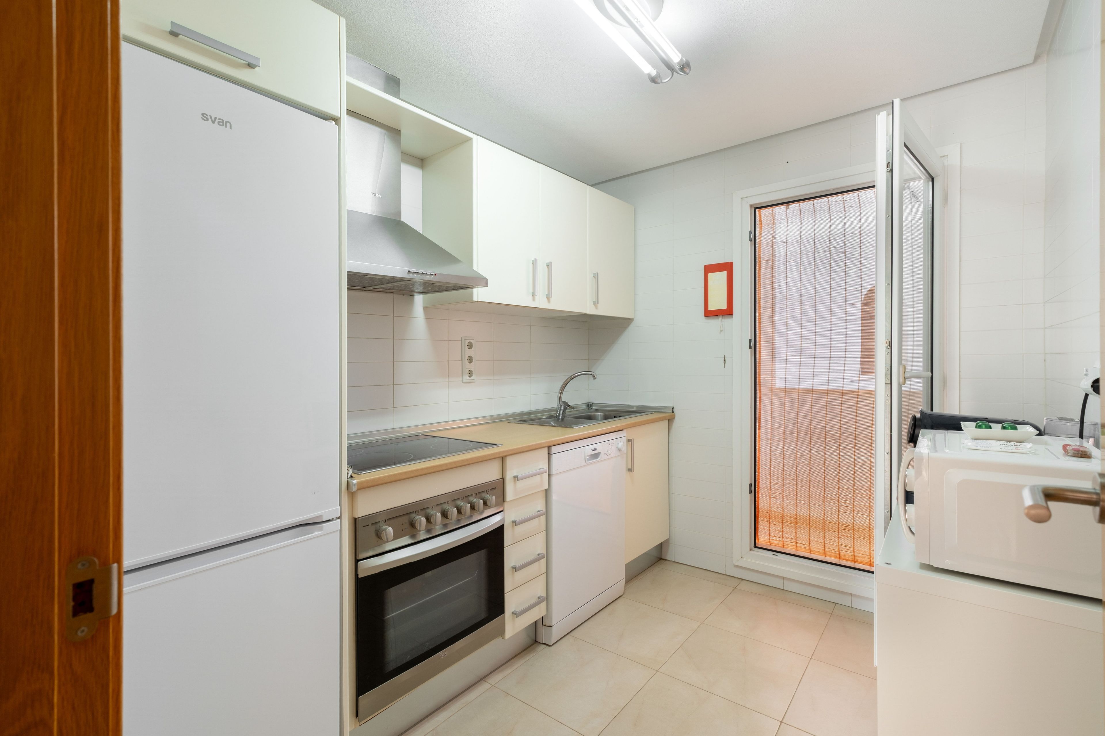 Una cocina moderna con electrodomésticos blancos, estufa, horno y lavavajillas.
