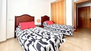 Une chambre d’hôtel avec deux lits, une armoire et une porte donnant sur une autre pièce.