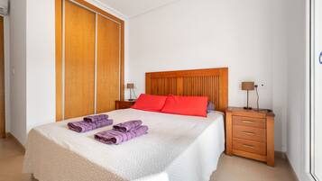 Una habitación de hotel con una cama, una mesita de noche, una lámpara y un armario.