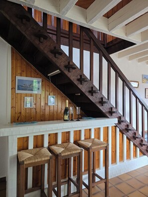 A wooden staircase with a bar area at the bottom, featuring two stools and a bottle of champagne. - "Chez papi Rob", Landes house with pétanque court, a stone's throw from the center. (Andernos-les-Bains)
