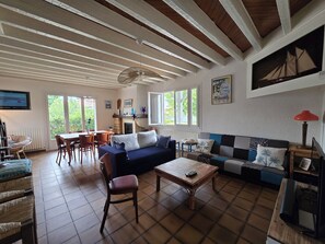 A cozy living room with a sofa, chairs, a coffee table, and a dining area with a table and chairs. - "Chez papi Rob", Landes house with pétanque court, a stone's throw from the center. (Andernos-les-Bains)