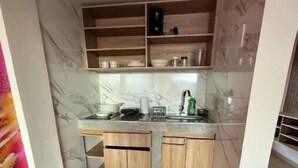 A compact kitchen with marble backsplash, wooden cabinets, and a countertop with various kitchen items. - Historic Downtown - Modern Loft - Toque Cocha - Quillak (Nariño)
