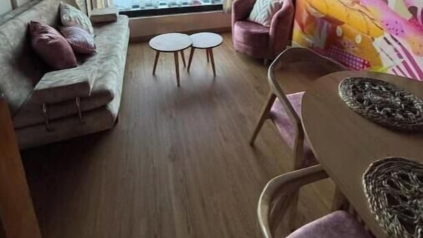 A living room with a sofa, chairs, a small table, and a view of a building through large windows. - Historic Downtown - Modern Loft - Toque Cocha - Quillak (Nariño)