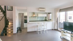 Un appartement moderne doté d’une cuisine, d’un coin repas et d’un téléviseur.
