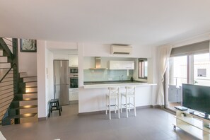 A modern apartment with a kitchen, dining area, and a TV. - Apartment 'Cala Gaviota' with Sea Views, Wi-Fi, and Air Conditioning (Colònia de Sant Jordi)