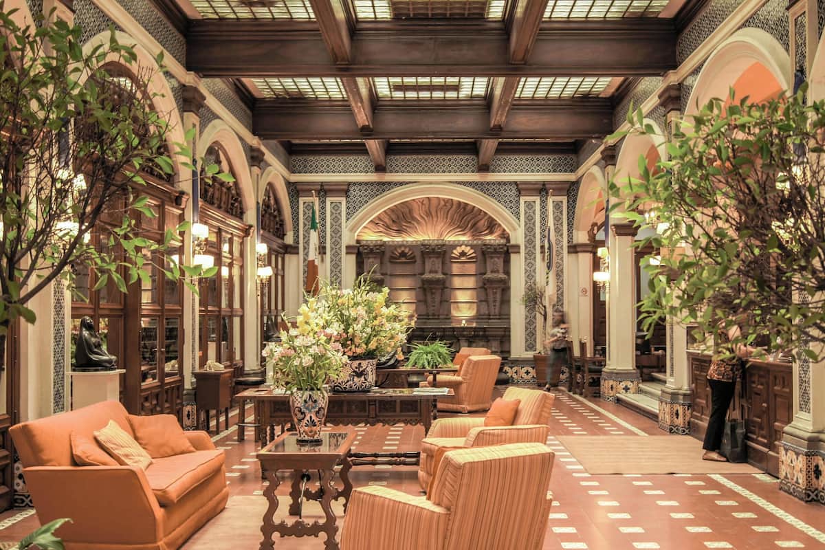 Un interior con techos abovedados, muebles de madera y un arreglo floral central.