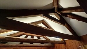 Une structure de plafond en bois avec des poutres apparentes et une lucarne triangulaire.
