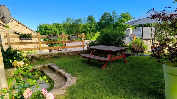 Un jardin avec une clôture en bois, une table de pique-nique et un chemin en pierre.