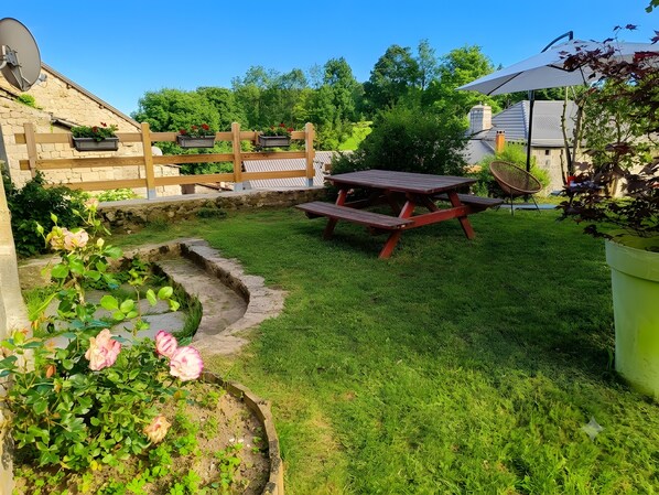 A backyard with a wooden fence, a picnic table, and a stone pathway.