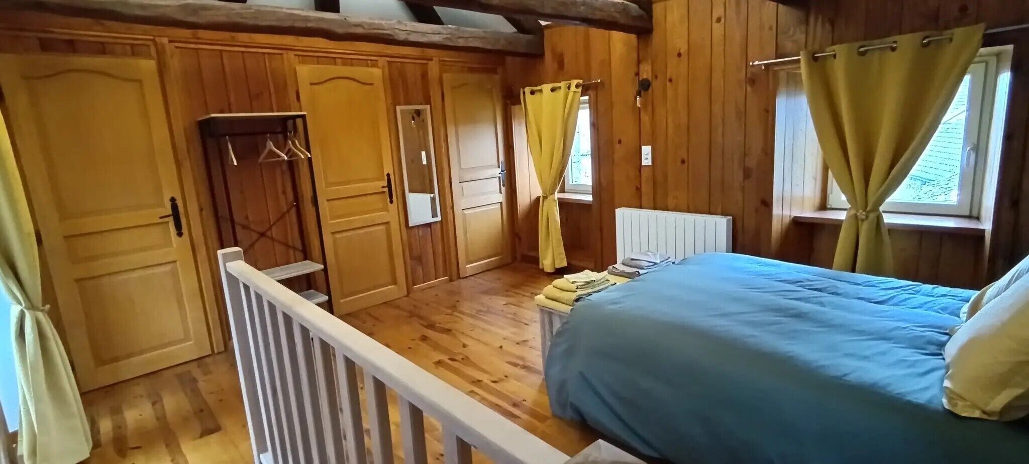 Een slaapkamer in een houten chalet, met een bed, een kledingkast en een raam met gordijnen.